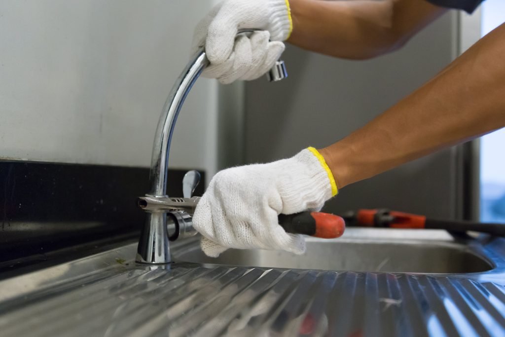 west-auckland-plumber-fixing-white-sink-pipe-with-adjustable-wrench